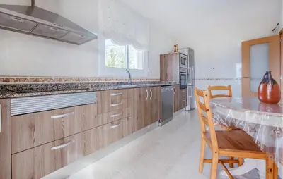 a kitchen with wooden cabinets and a table and a wooden chair at Cozy Home In Calafell With Wifi in Calafell