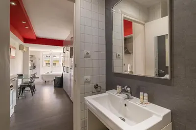 a bathroom with a white sink and a living room at Stay U-nique Apartment Creu Coberta in Barcelona