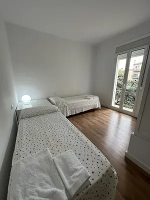two beds in a white room with a window at LEsglesia 1 in Arenys de Mar