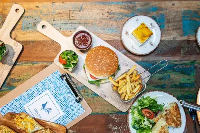 a table topped with plates of food and a hamburger and french fries at Safestay Barcelona Passeig de Gràcia in Barcelona