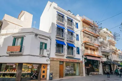 a white building on a street with a store at InSitges Center in Sitges