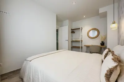 a bedroom with a white bed and a table at Novus Homes Barcelona Plaza España in Barcelona