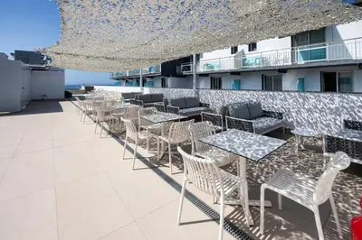 a row of tables and chairs on the roof of a building at Hotel Calella by Beatriz Hoteles in Calella