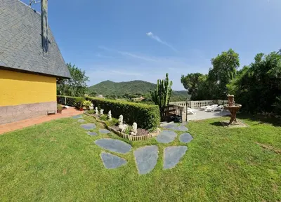 a garden with rocks in the grass next to a house at Villa cascada in Sant Cebrià de Vallalta