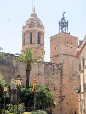 an old building with two towers and a palm tree at Pis Sitges centre in Sitges