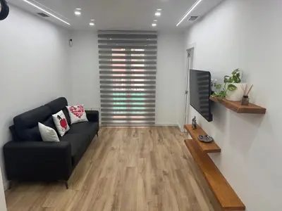 a living room with a black couch and a tv at Apartamento Plaza España - Bordeta BCN in Barcelona
