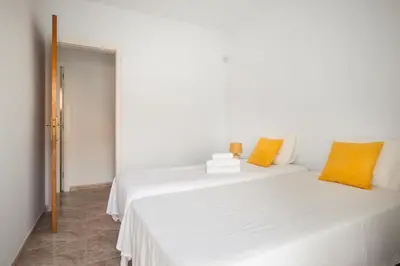 a bedroom with two white beds with orange pillows at Marina beach Castelldefels in Castelldefels