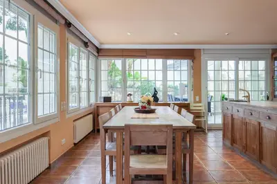a large kitchen with a wooden table and windows at Villa Drago in Castelldefels