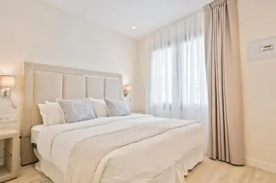 a white bedroom with a large bed and a window at Sitges Spaces Urban Beach Flat- 3 Bedrooms, 3 Bathrooms, Huge Terrace, Near Beach in Sitges