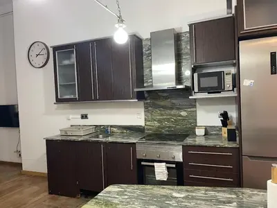 a kitchen with wooden cabinets and a clock on the wall at SA 15min downtown Barcelona, 5min Metro, Beach nearby in Sant Adria de Besos