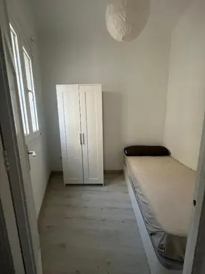 a small bedroom with a bed and a cabinet at Room Montjuic in Barcelona