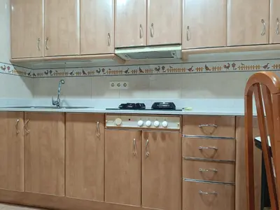a kitchen with wooden cabinets and a sink at Habitación y baño privado in Vilanova del Camí