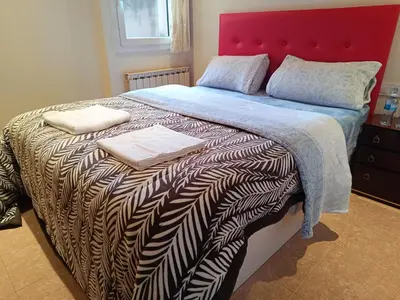 a bedroom with a large bed with a red headboard at Habitación y baño privado in Vilanova del Camí