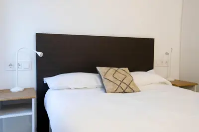 a large bed with a black headboard and white pillows at Panoramic view Gavà Mar in Gavà