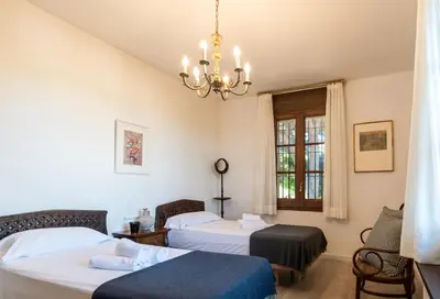 a bedroom with two beds and a chandelier at El Mirador Esencia Mediterránea in Arenys de Mar