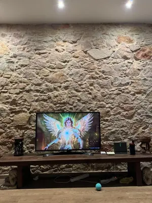 a television with an angel on a stone wall at Rustic Casita Gavà in Barcelona