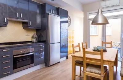 a kitchen with a table and a stainless steel refrigerator at Rustic Casita Gavà in Barcelona