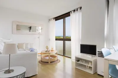 a white room with a bed and a television at Bright Apartment In Gava Mar in Gavà