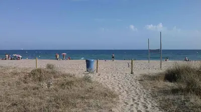 a sandy beach with people on the water at Bright Apartment In Gava Mar in Gavà