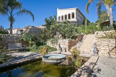 a house with a pond in front of a building at Alcazar Del Garraf in Olivella