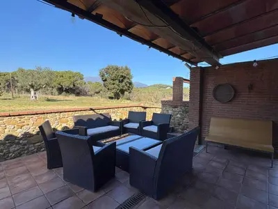 a patio with a table and chairs and a stone wall at Ca l'Esclatat in Santa María de Palautordera