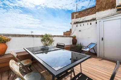 a patio with a glass table on a wooden deck at Gràcia Monthly 1BR Sunny Private Terrace in Barcelona