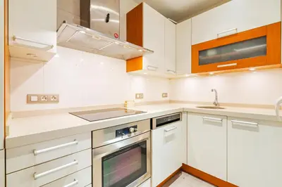 a kitchen with white cabinets and a sink and a stove at Quiet, vibrant 2 bedroom in pedestrian Eixample in Barcelona