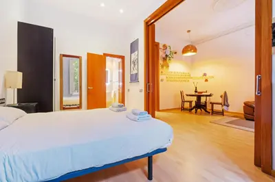 a bedroom with a bed and a dining room at Quiet, vibrant 2 bedroom in pedestrian Eixample in Barcelona