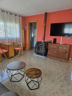 a living room with red walls and a tv and tables at Casa del Campo in Els Hostalets
