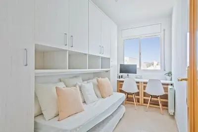 a white living room with a couch and a desk at Apartamento Cubelles Molí Baix in Cubelles