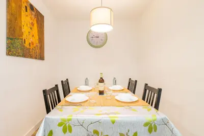 a dining room with a table and a clock on the wall at Apartamento 3 hab Fira de Bcn a 20 minutos de Bcn Centro in Hospitalet de Llobregat
