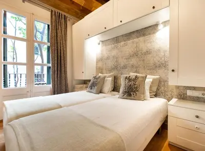 two beds in a room with two windows at Blasco de Garay: acogedor apartamento en el corazón de Poble-sec in Barcelona