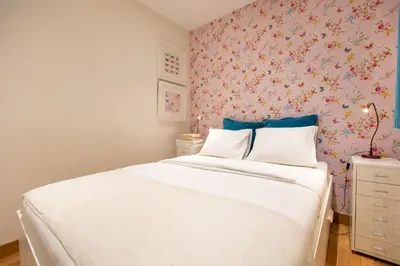 a bedroom with a white bed with a floral wallpaper at Blasco de Garay: acogedor apartamento en el corazón de Poble-sec in Barcelona