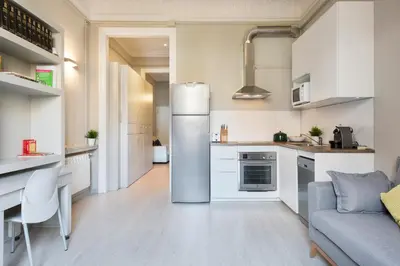 a kitchen with white cabinets and a refrigerator at Suites4days Ali bei Apartment in Barcelona