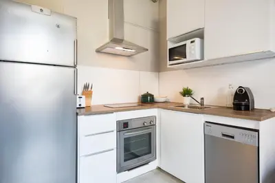 a white kitchen with a window and a white chair at Suites4days Ali bei Apartment in Barcelona