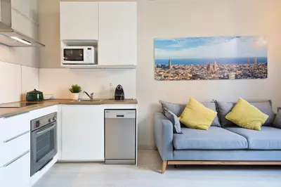 a kitchen with a refrigerator and a couch at Suites4days Ali bei Apartment in Barcelona