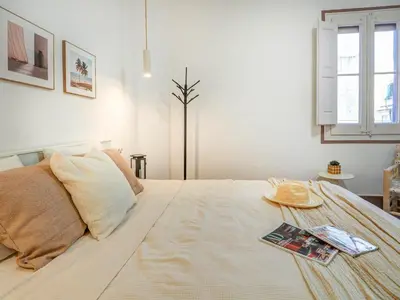 a bedroom with a large white bed with a magazine on it at Las Ventanas Sea Front by Hello Homes Sitges in Sitges