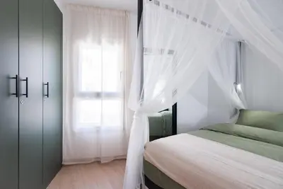 a bedroom with a bed with white curtains and a window at Casa Jasmine Family Villa near the beach in Barcelona