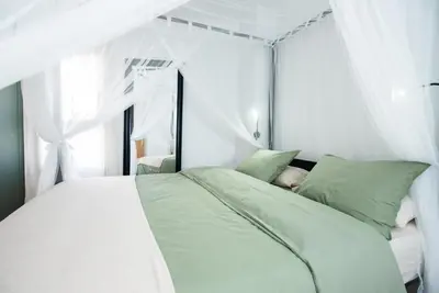a white bedroom with a bed with white curtains at Casa Jasmine Family Villa near the beach in Barcelona