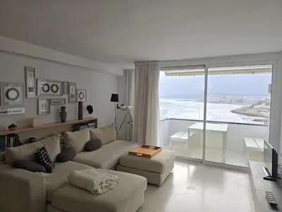 a living room with a couch and a large window at Sunset apartment by Hello Homes Sitges in Sitges