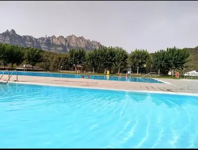 a large blue swimming pool with mountains in the background at Cal Rami in Castellbell i Vilar