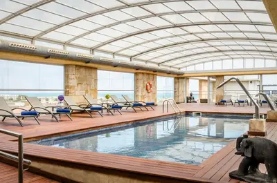 a pool in a building with chairs and a swimming pool at Exe Cunit Suites & Spa in Cunit