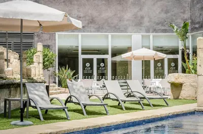 a group of chairs and umbrellas next to a pool at Exe Cunit Suites & Spa in Cunit