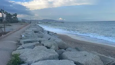 a beach with rocks on the sand and the ocean at Apt compartido martirrena in Badalona