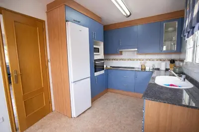 a kitchen with blue cabinets and a white refrigerator at Nature & Tranquility only 25km from Barcelona in Torrelles de Llobregat