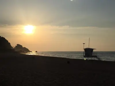 a sunset on the beach with a lifeguard station at Casa Feliz del Mar in San Pol de Mar