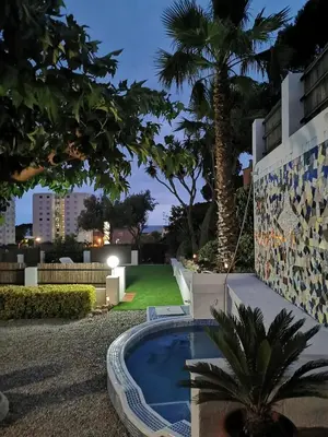 a backyard with a swimming pool and a palm tree at Casa Feliz del Mar in San Pol de Mar