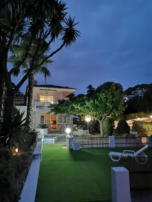 a house with a lawn and palm trees at night at Casa Feliz del Mar in San Pol de Mar