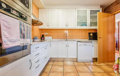 a kitchen with white cabinets and a sink at Stunning Home In Arenys De Munt in Arenys de Munt