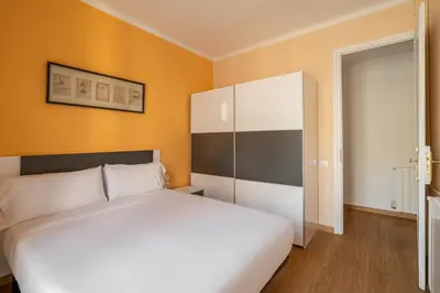 a bedroom with a white bed and an orange wall at Stay U-nique Apartments Lepant II in Barcelona